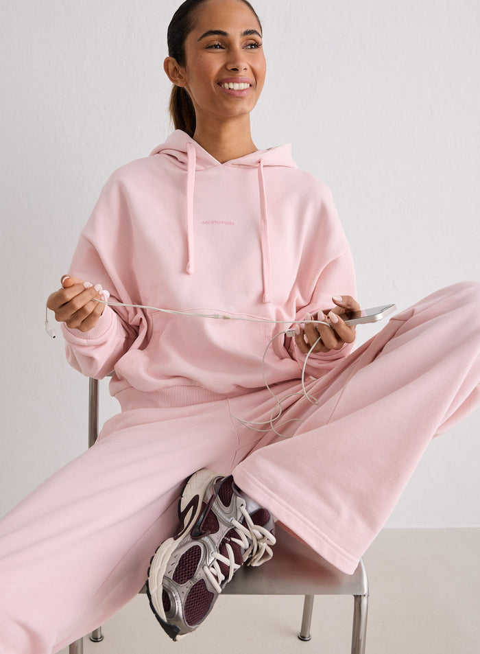 Nainen istumassa tuolilla yllään vaaleanpunainen aim'n Ballerina Apparel Chunky Terry Hood [S-170cm]