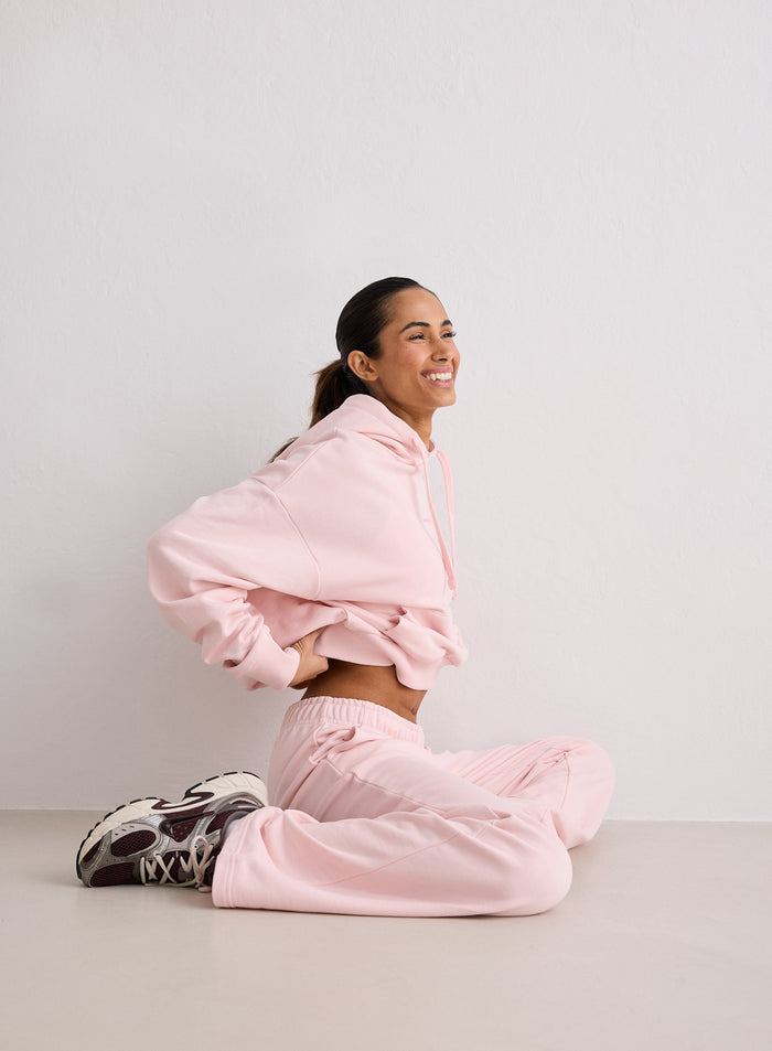 Lattialla istuva nainen yllään vaaleanpunainen huppari ja aim'n Ballerina Chunky Terry Sweatpants. [S-170cm]