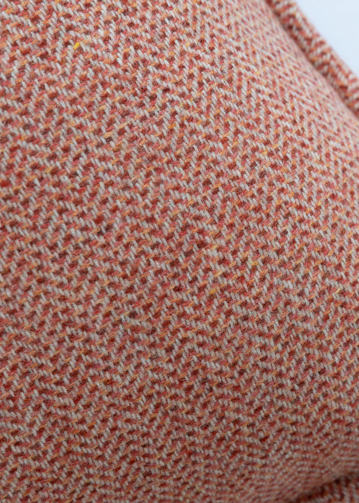 Close-up of a textured red-brown fabric with a subtle pattern on a white background