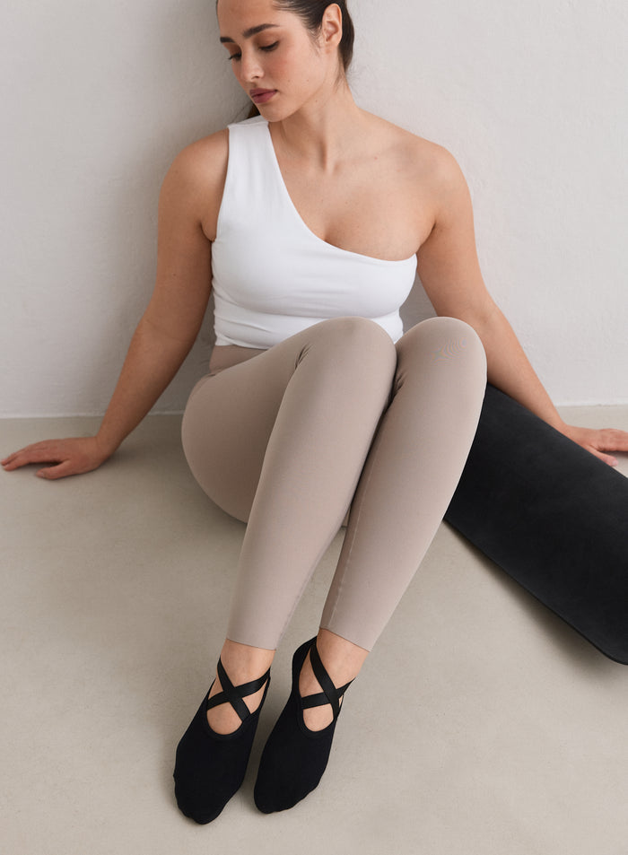 Malli yllään mustat aim'n Pilates Socks -sukat istumassa lattialla.