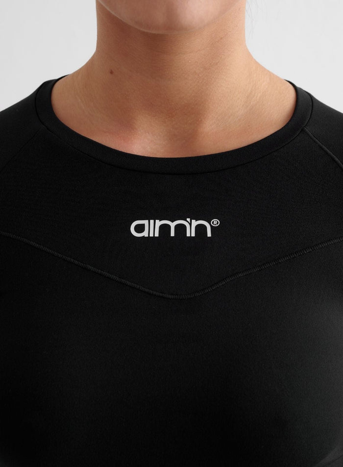 Musta Soft Basic Long Sleeve -paita valkoisella aim'n-logolla ja koristetikkauksilla.