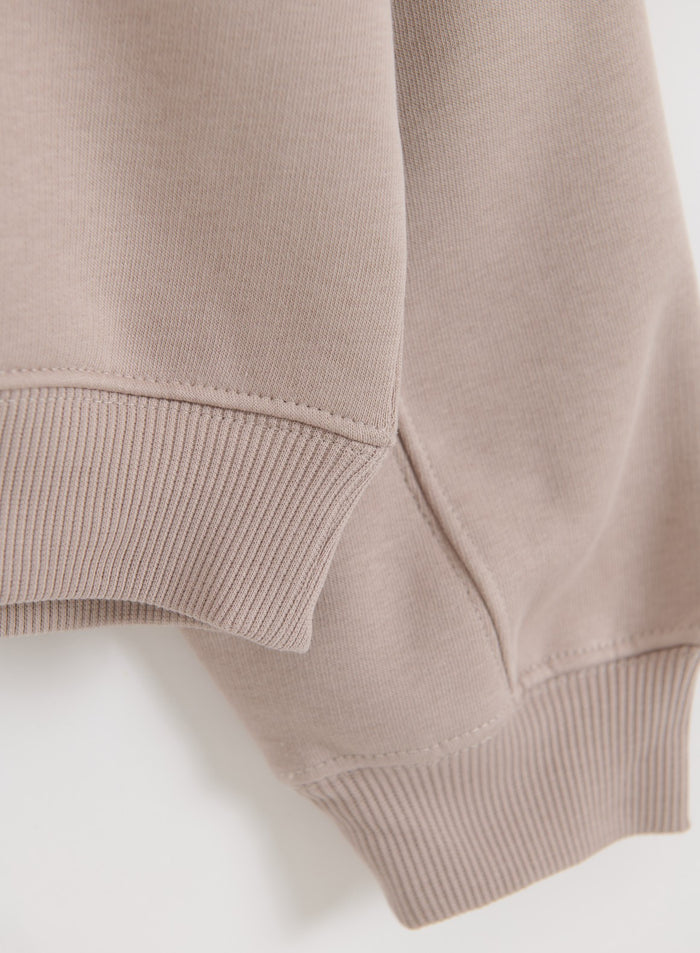 Yksityiskohta aim'n Dark Clay Varsity Sweat Half Zip -paidan pehmeästä jerseymateriaalista ja resoreista.