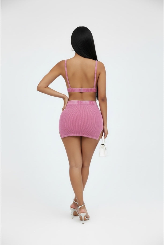 Person wearing a pink two-piece outfit on a white background