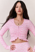 Woman wearing a pink bow patterned workout jacket and matching leggings against a plain background