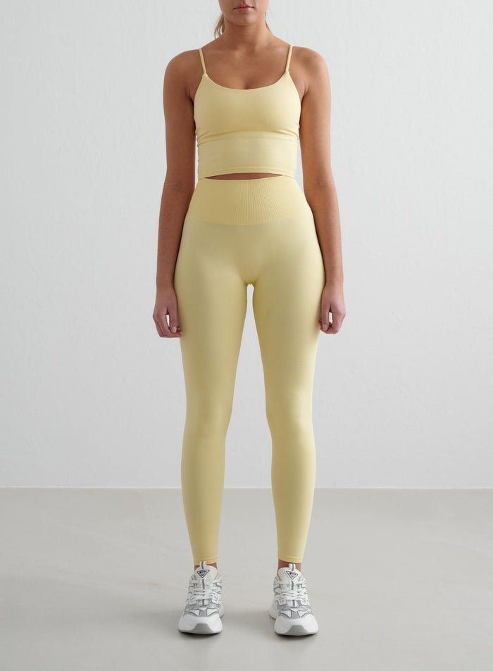 Keltaiset aim'n Mellow Shape Seamless Tights -trikoot korkealla resorivyötäröllä ja yhteensopiva toppi.