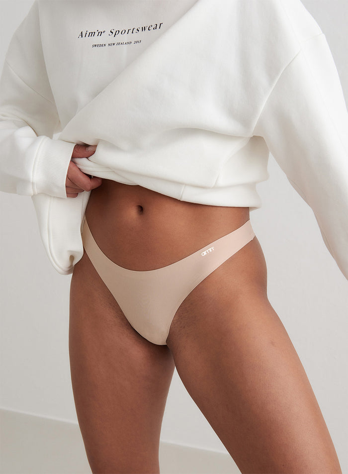 Malli yllään nuden beiget Invisible Thong -stringit ja valkoinen aim'n-collegepaita.