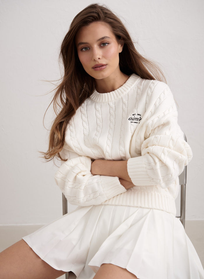 Luonnonvalkoinen Club Cable Knit Sweater aim'n-logolla ja valkoinen vekkihame. [M-174cm]