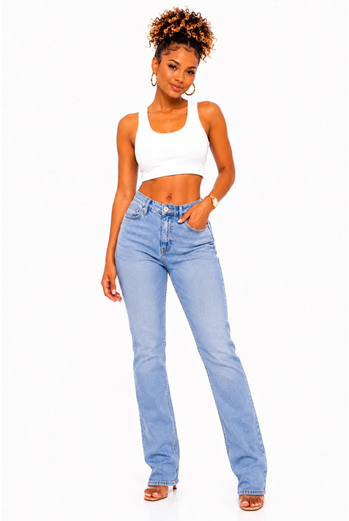 A woman modeling a pair of light-wash blue high-rise jeans with a white crop top, standing against a plain white background.