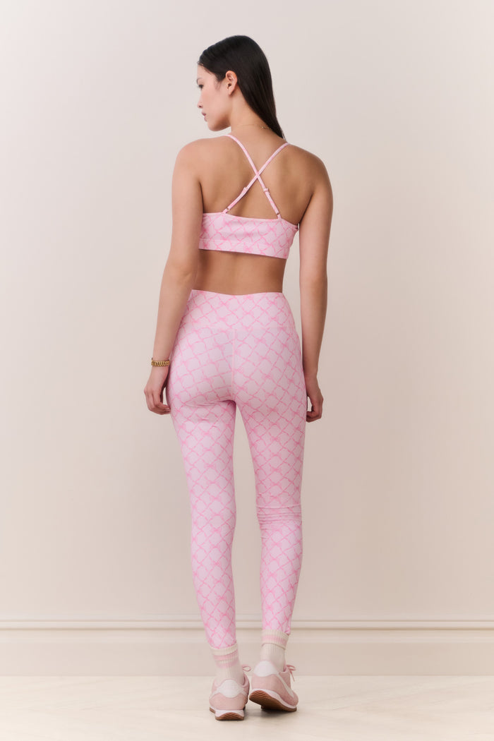 Woman wearing a pink sports bra and leggings set on a plain background