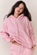 Person wearing a pink bow print jacket and matching sweatpants against a plain background