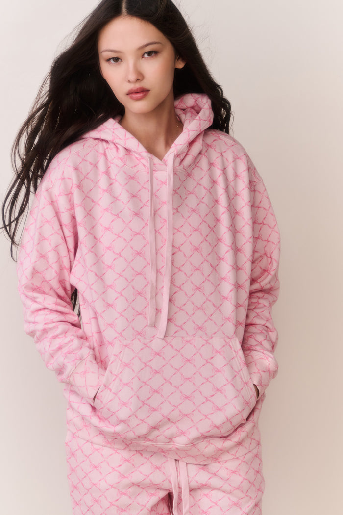 Person wearing a pink bow print jacket and matching sweatpants against a plain background