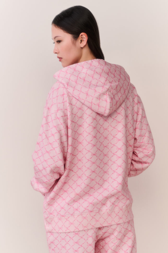 Person wearing a pink bow print jacket and matching sweatpants against a plain background