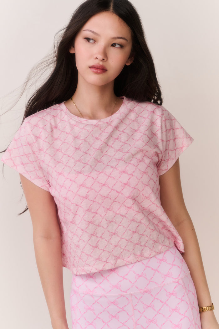 Woman wearing a pink bow patterned t-shirt and matching leggings outfit against a plain background