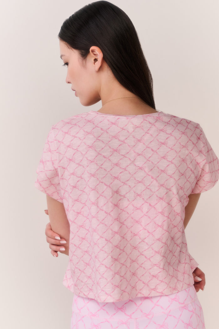 Woman wearing a pink bow patterned t-shirt and matching leggings outfit against a plain background