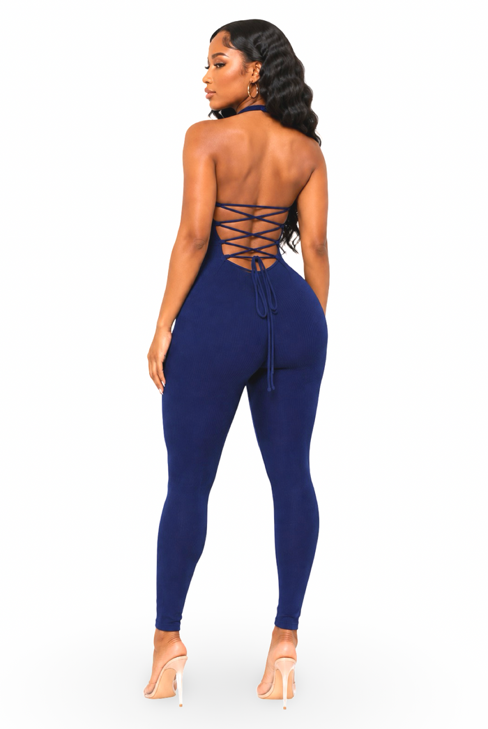 A woman modeling navy blue high-waisted leggings from the back, featuring a lace-up back design, on a solid white background.