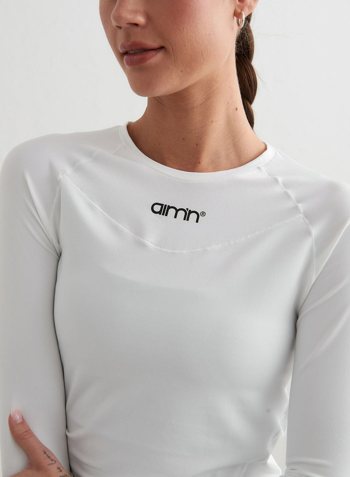 Valkoinen aim'n Soft Basic Long Sleeve -paita lähikuvassa mustalla logolla ja raglan-saumoilla.
