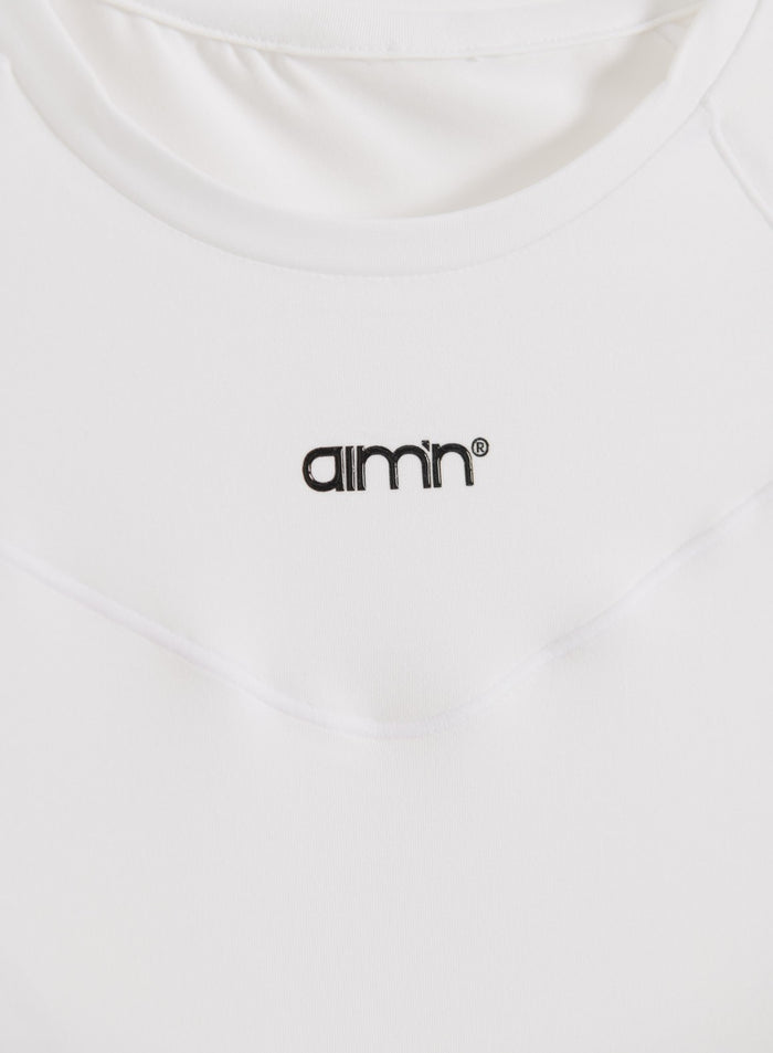 Valkoinen Soft Basic Short Sleeve -paita, lähikuvassa pyöreä pääntie ja musta painettu aim'n-logo.